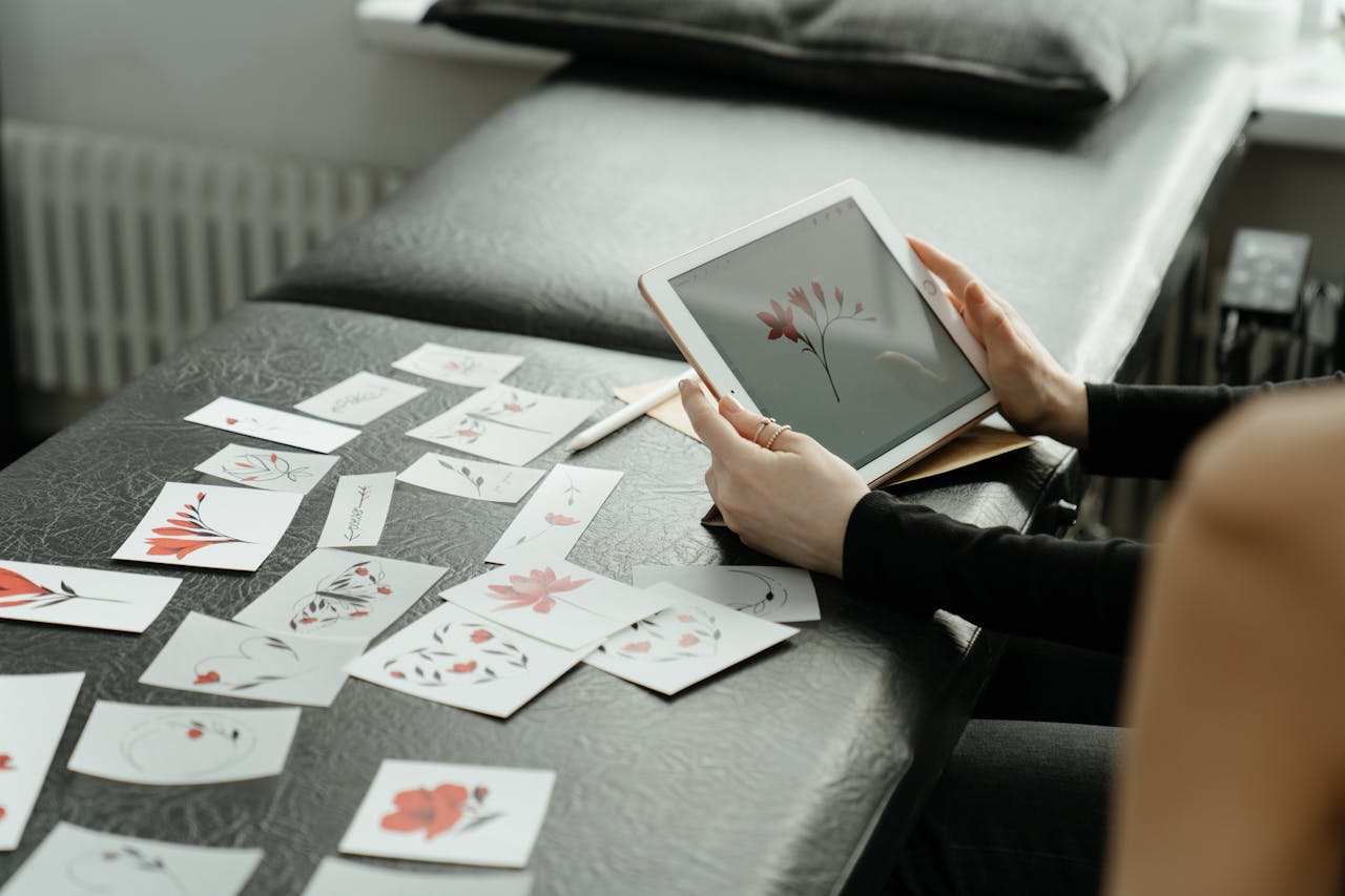 Artist finalizing floral tattoo designs on a digital tablet in a studio setting.